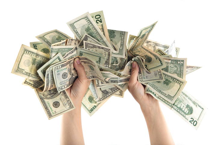 Two hands grasp a pile of American dollars.