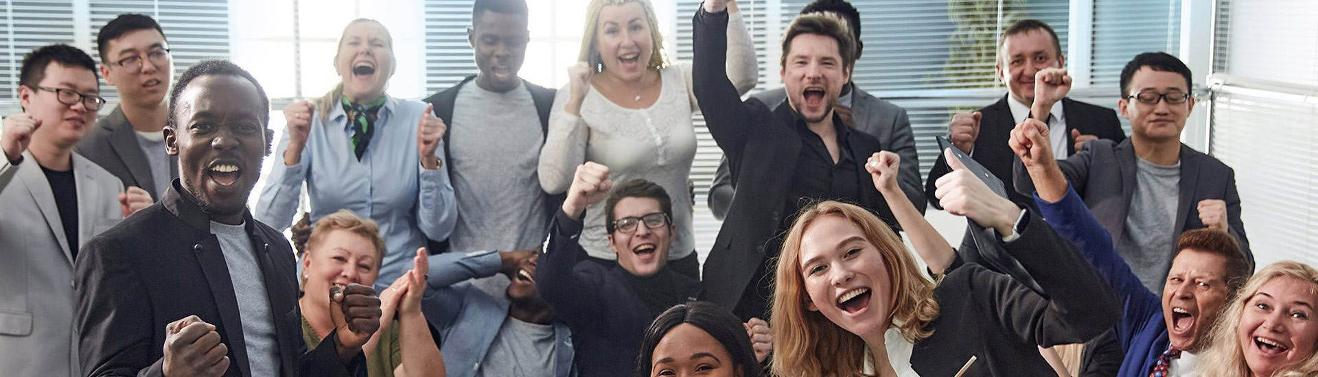 Eine Gruppe von Berufstätigen in Anzügen feiert und lächelt in die Kamera.