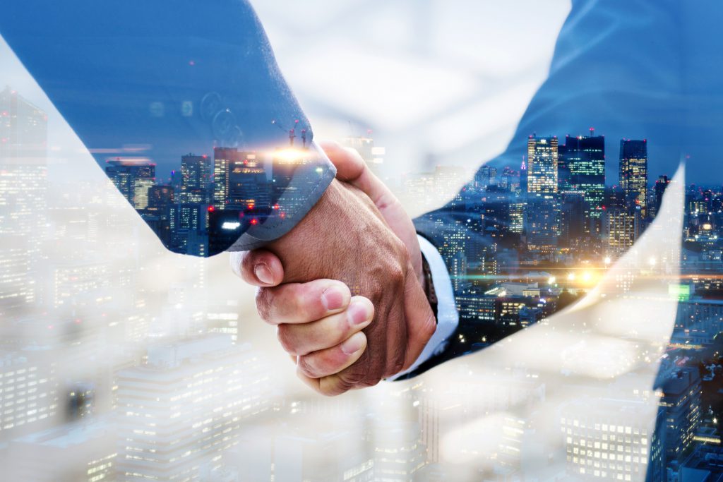 Partnership. multi exposure of investor businessman handshake with partner for successful meeting with night city background, digital technology, investment, negotiation, partnership, teamwork concept Two male hands shaking are superimposed upon a city scape background.