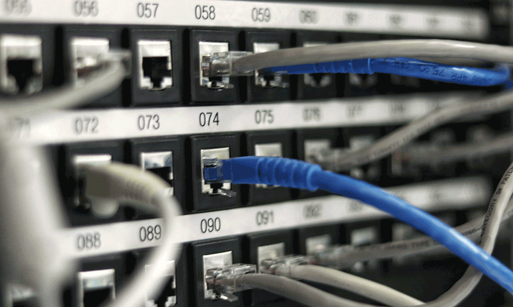 Numerous wires plug into numbered sockets in a computer data center.